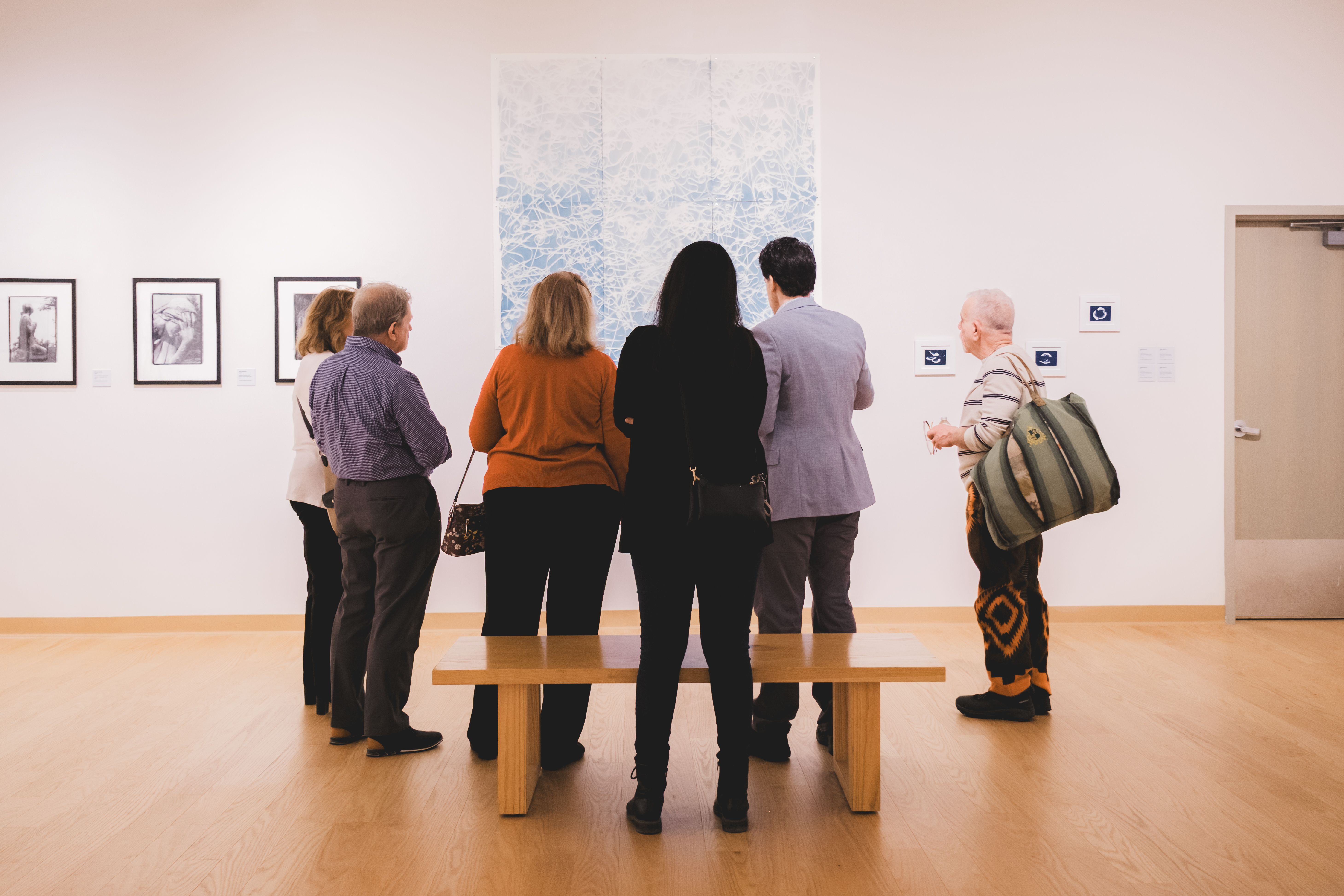 Group of people gathered together in a gallery for an exhibition opening