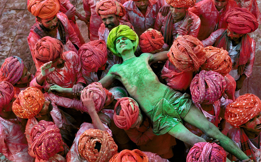 Steve McCurry Rajathan/1996 Crowd carries man during the Holi festival