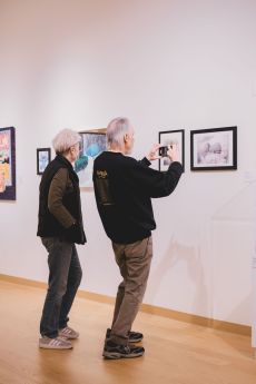 Group of people gathered together in a gallery for an exhibition opening