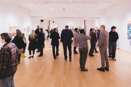 Group of people gathered together in a gallery for an exhibition opening