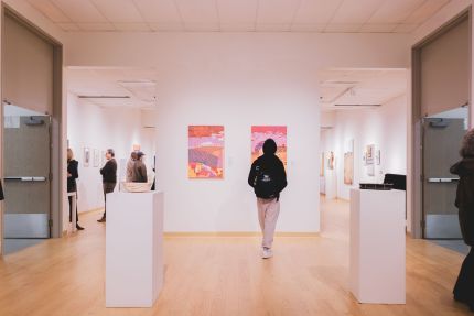 Group of people gathered together in a gallery for an exhibition opening