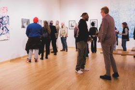 Group of people gathered together in a gallery for an exhibition opening