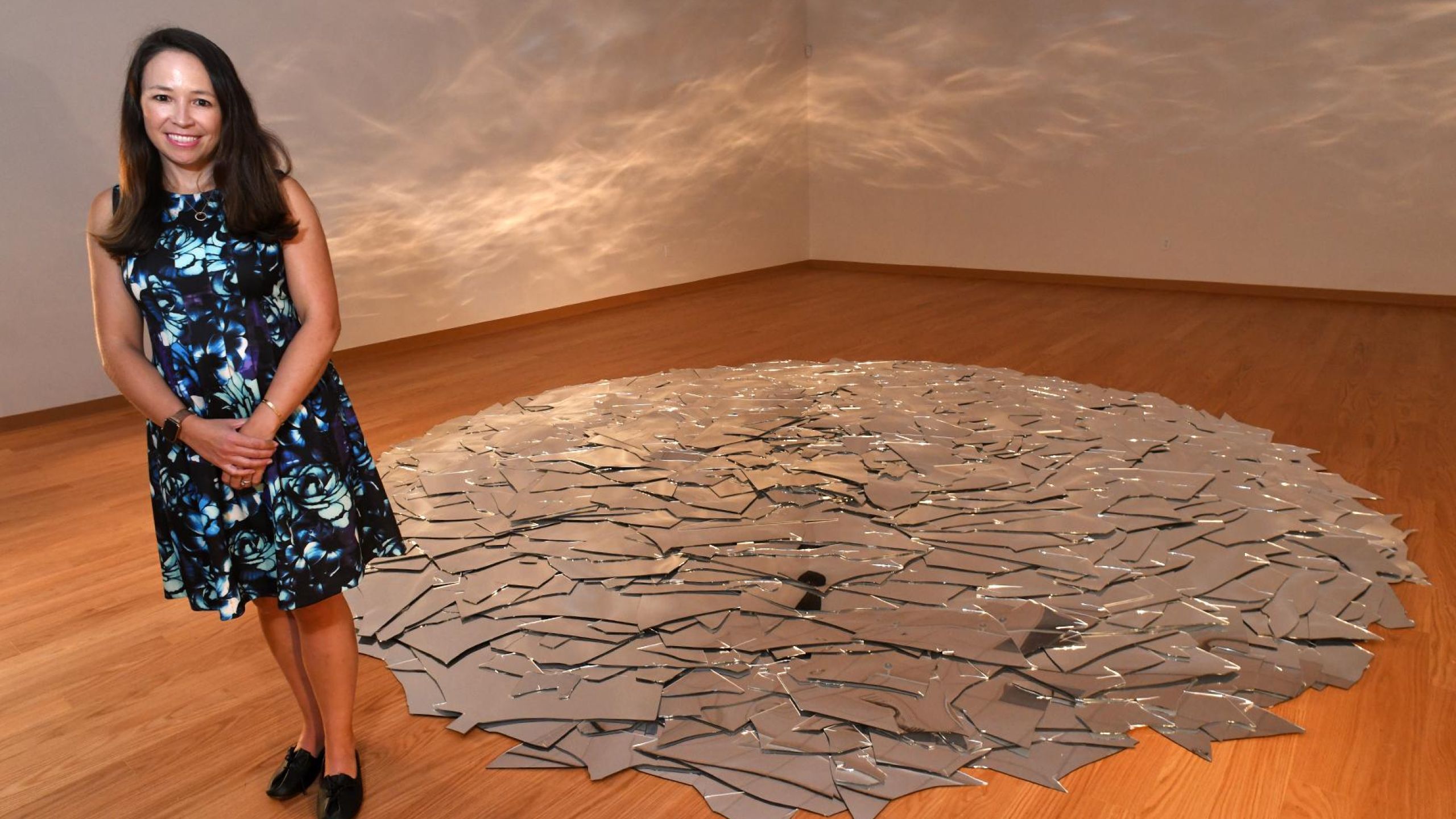 Jennifer Reynolds-Kaye, the new director of the Housatonic Museum of Art, poses inside the Chernow Galleries next to installations currently on display by Stamford artist June Ahrens,