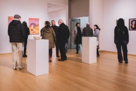 Group of people gathered together in a gallery for an exhibition opening