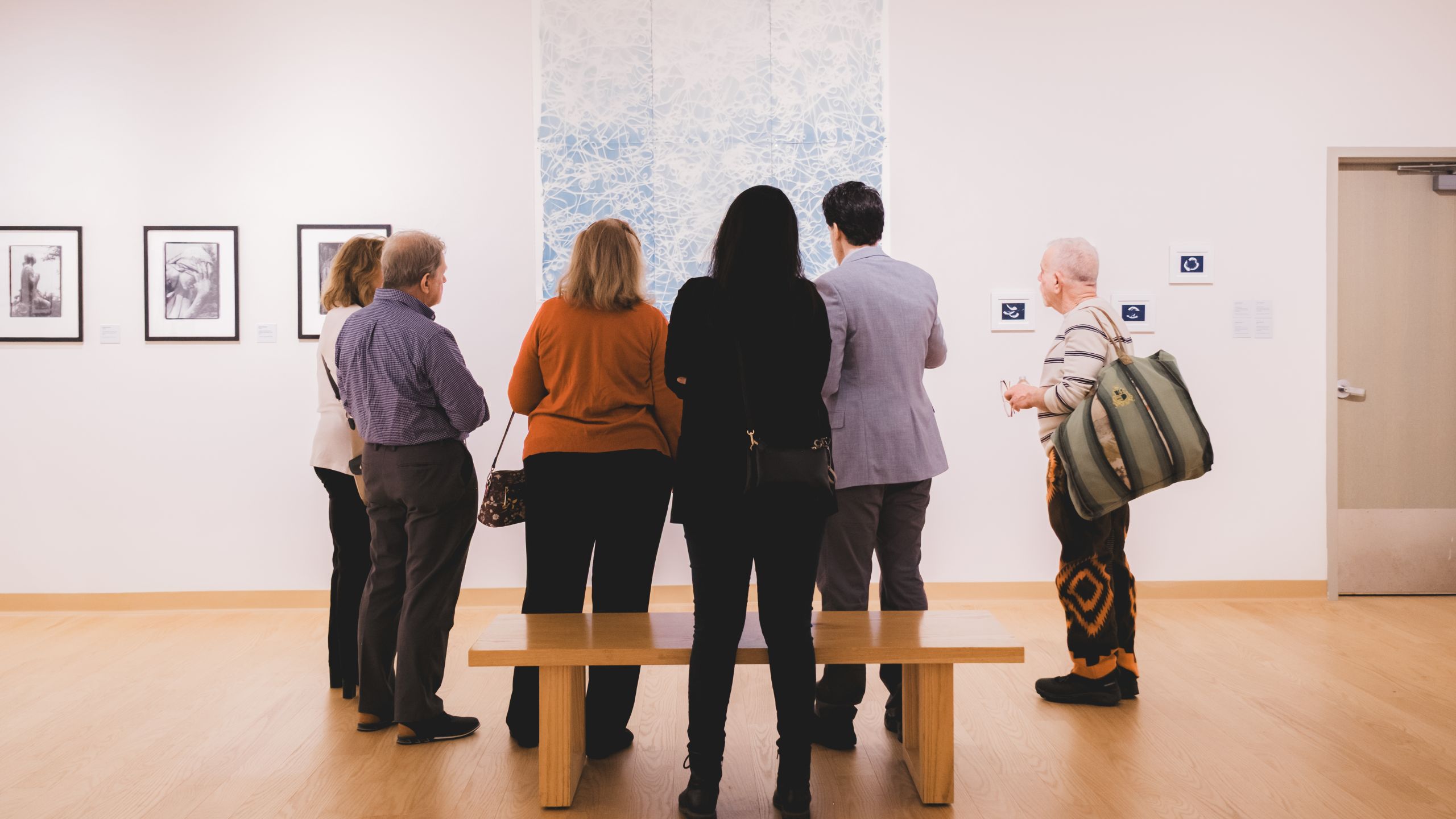 Group of people gathered together in a gallery for an exhibition opening